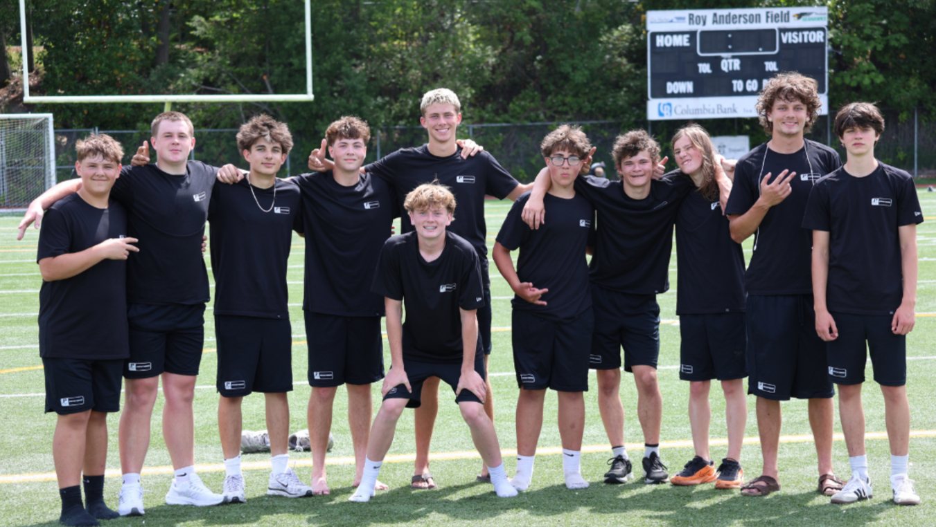 Darkened background photo: a group of Peninsula football players at Roy Anderson Field